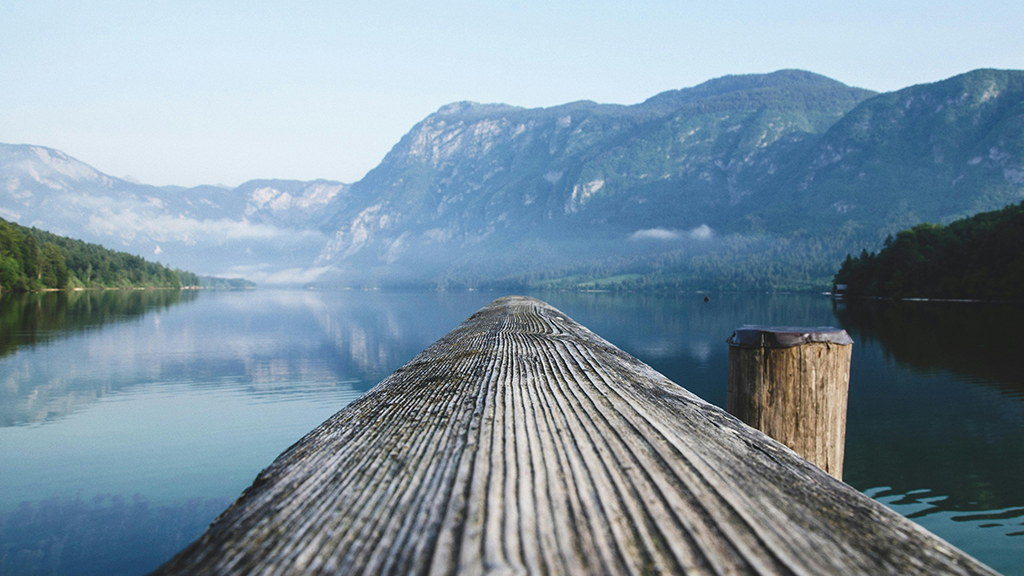 Holzgeländer mit Sicht auf See und Berg